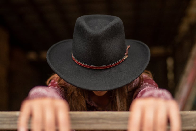 Woman in black wool felt hat, head tilted down. 