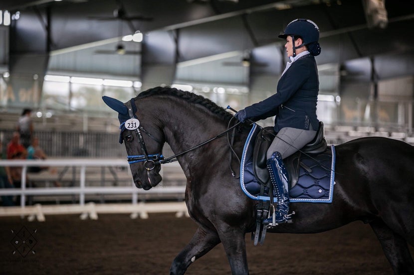 Women riding her Dressage test in a navy blue and gray show outfit.
