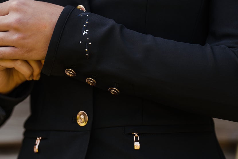 Horseback rider showing off the sparkle crystals on the sleeve of their show coat. 