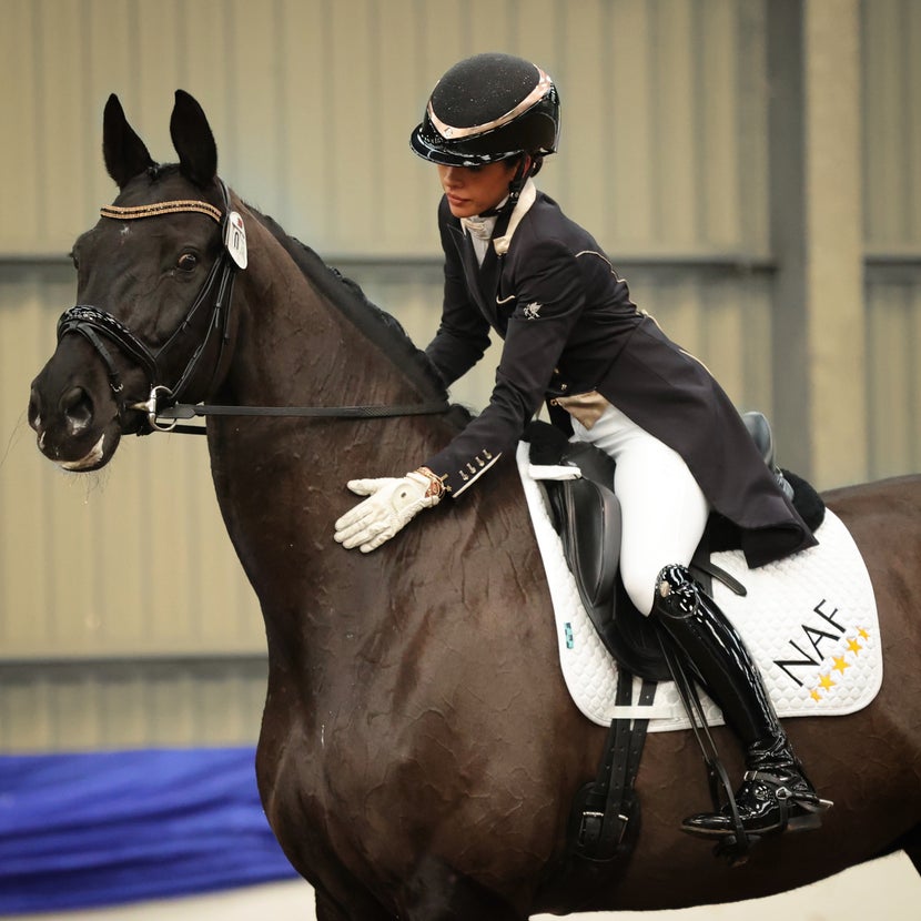 Dressage rider patting her black horse. 