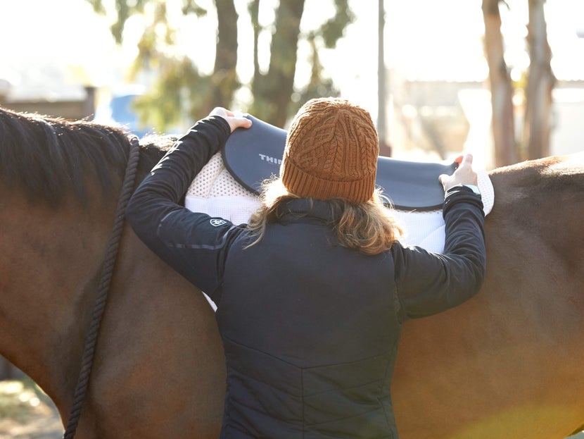 a rider places a foam half pad on top of and English saddle pad