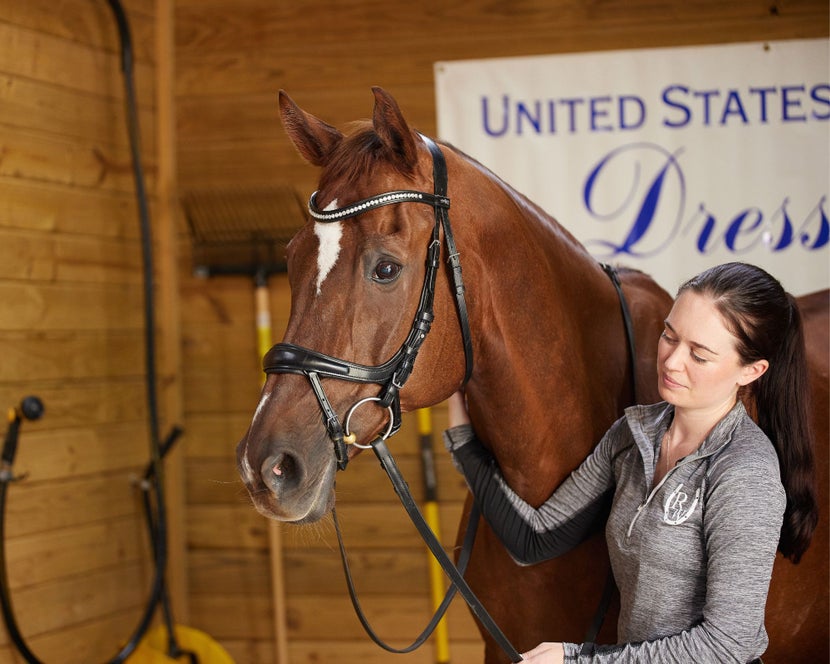 Rider standing next to her chestnut horse showing a correctly fitting anatomical brid;e.