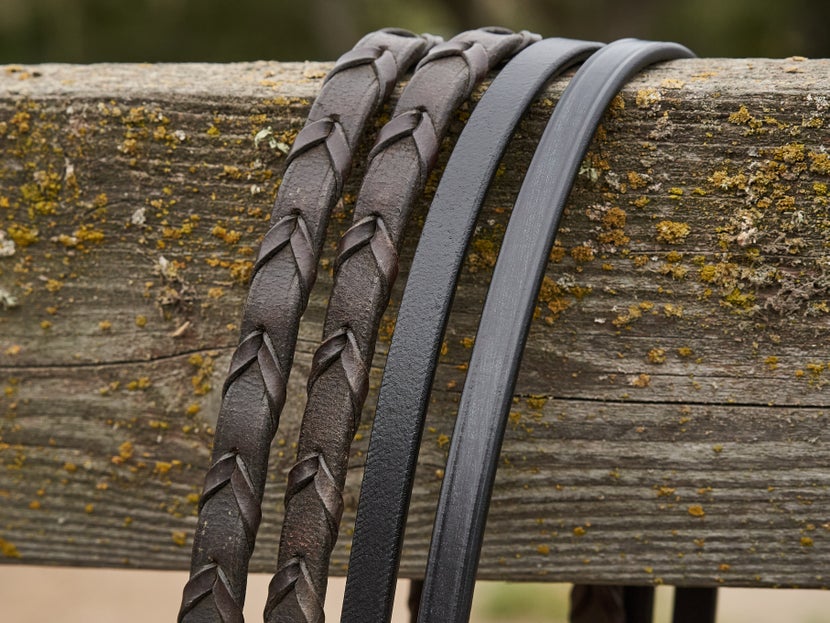 Leather reins, side by side, with braided leather reins on the left and smooth leather reins on the right. 