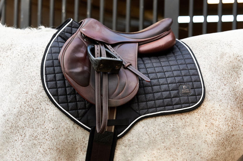 Silver Sparkly Majyk Equipe Close-Contact Saddle Pad on a grey horse under a brown jumping saddle.
