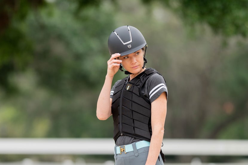 Woman wearing an equestrian safety vest and riding helmet