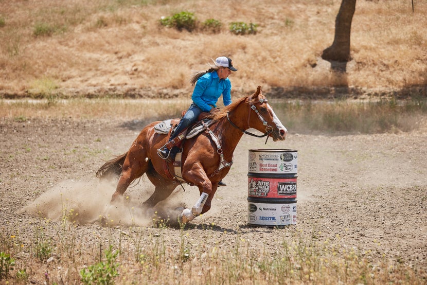 Krista and her chestnut horse turning around a barrel while practicing at home. 