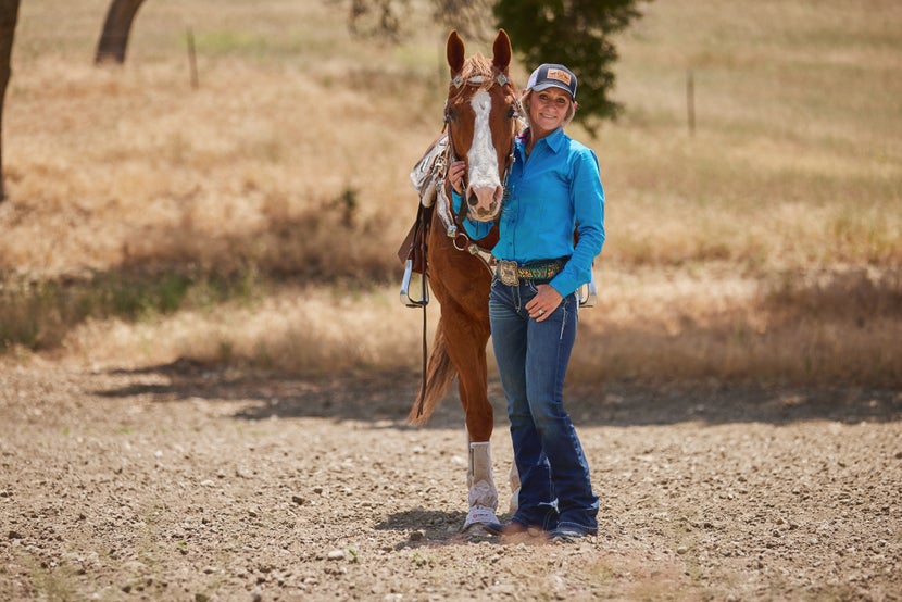 Krista and her chestnut horse standing side by side smiling. 