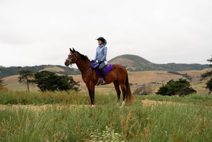 Rider wearing a Helmet Brims visor and pausing her horse on the trail