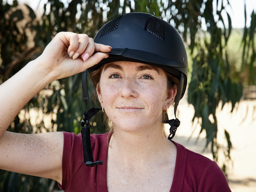 Tilting helmet on woman's head to check for proper fit. 
