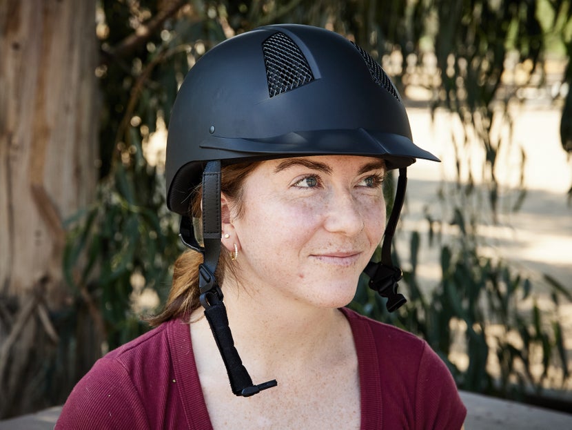 An unbuckled helmet sitting on woman's head.