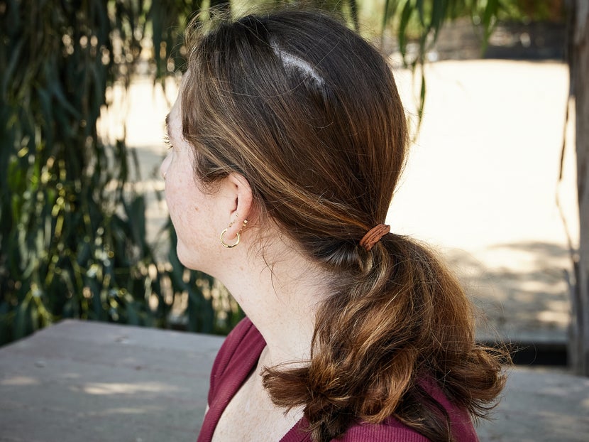 Woman's hair pulled back into a ponytail in prep for putting on a riding helmet. 