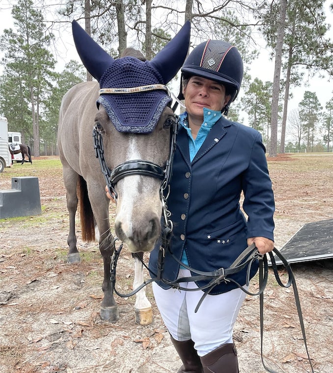 Meghan standing next to her bridled pony in show attire. 