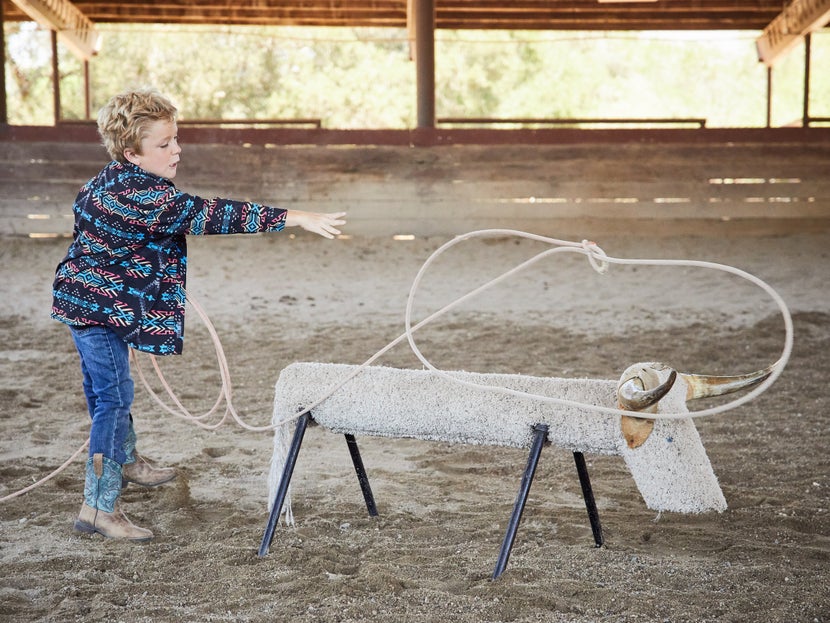 Male child practices roping a dummy cow.