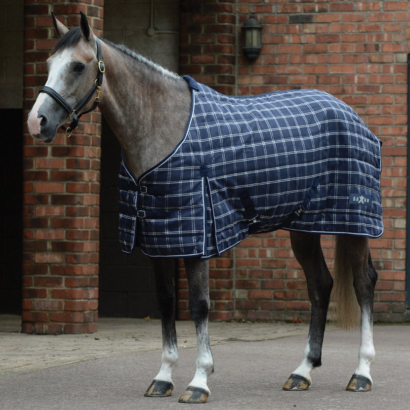 Grey horse standing in a barn courtyard wearing the Saxon Stable Standard Neck 1200 D Medium Blanket