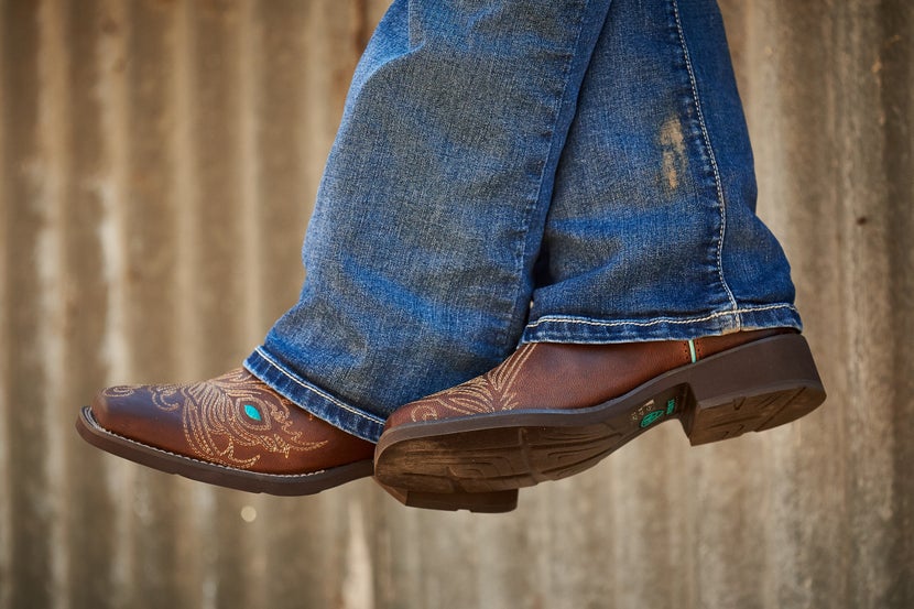 Woman's feet hanging over ledge in Ariat cowboy boots.