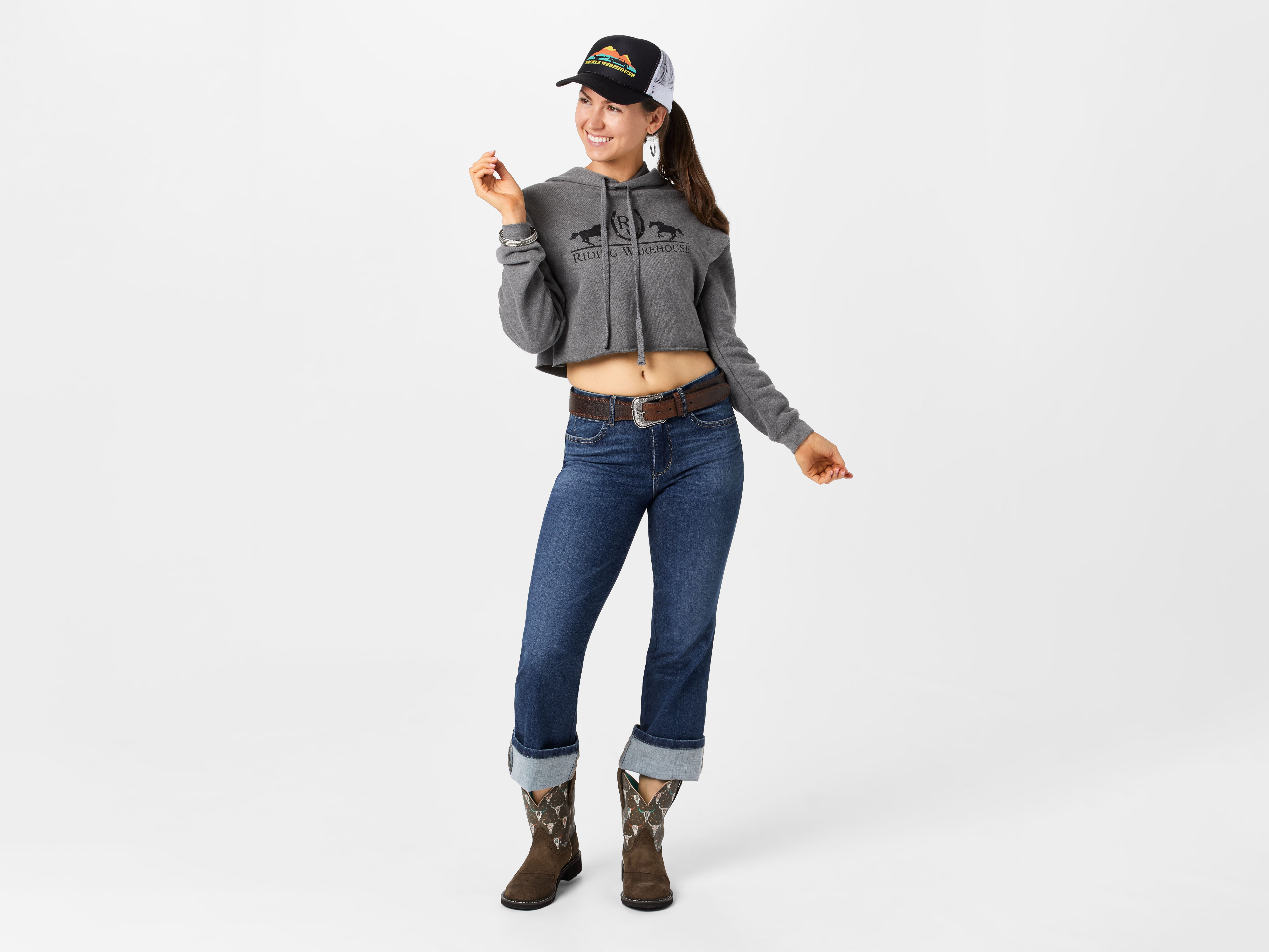 Lady wearing short cowboy boots styled with rolled up jeans and a cropped hoodie.