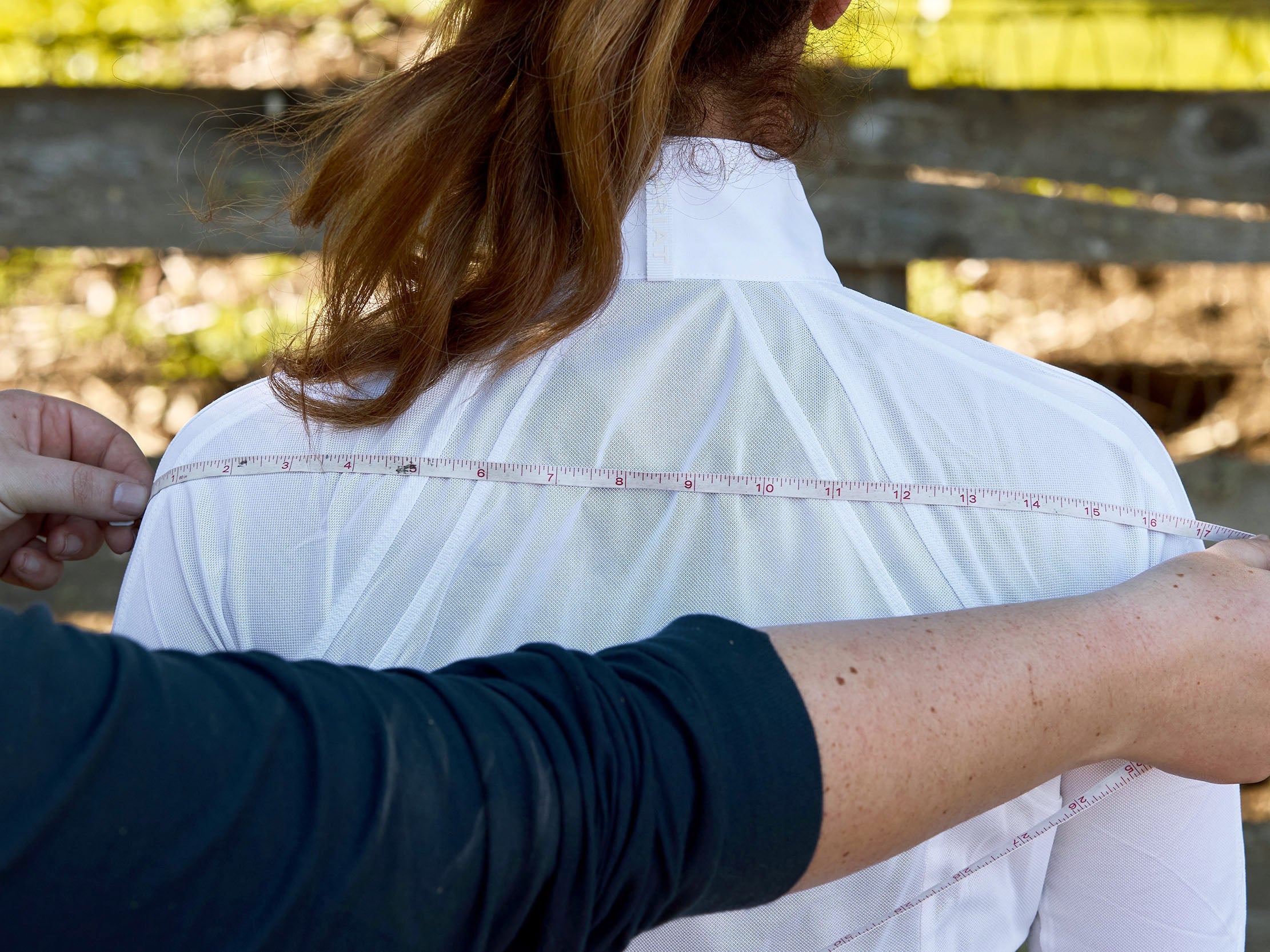 The shoulder width measurement for a horse show coat being taken on a rider.