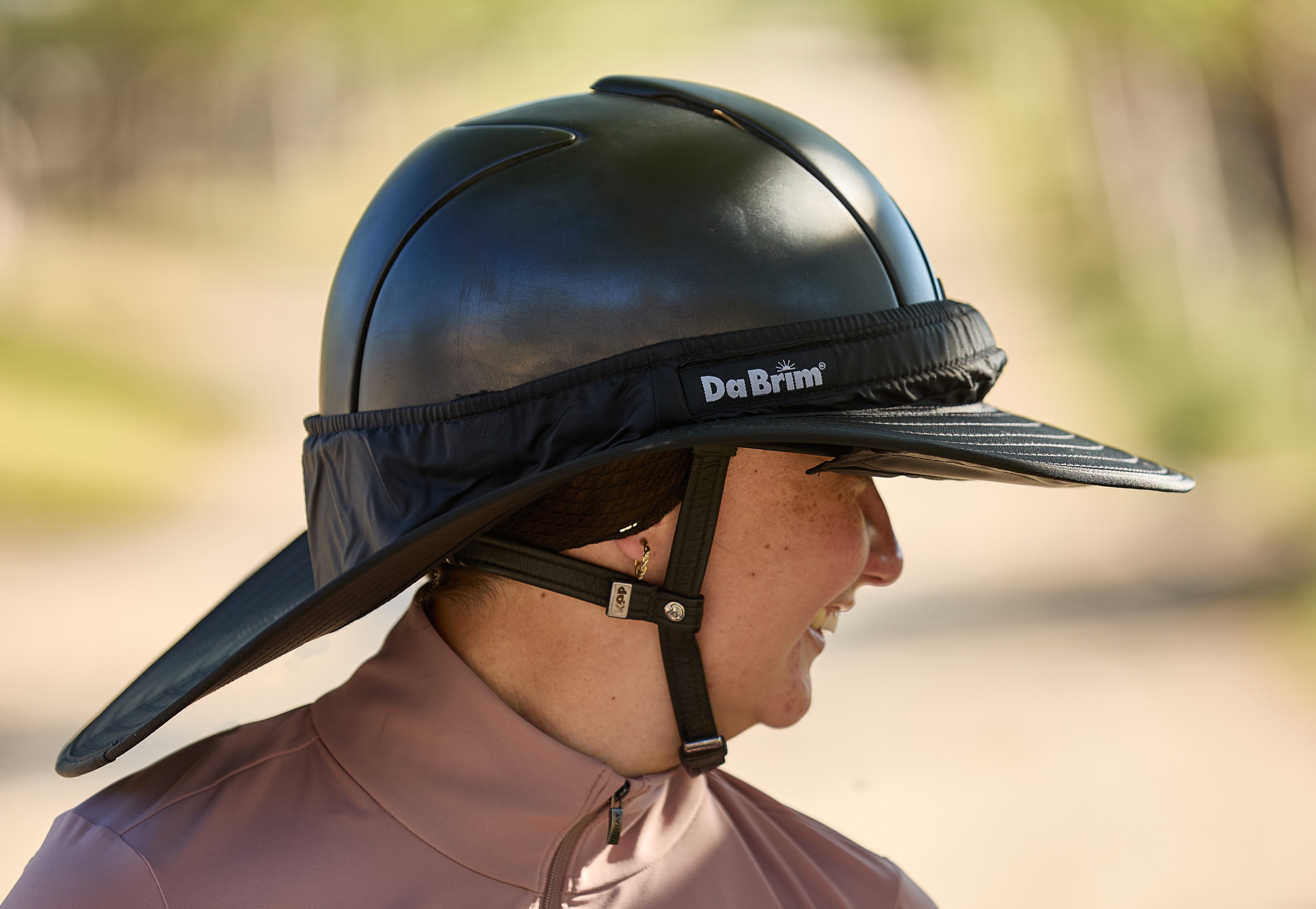 A horseback rider wearing a DaBrim Helmet Visor on her helmet offering full coverage.