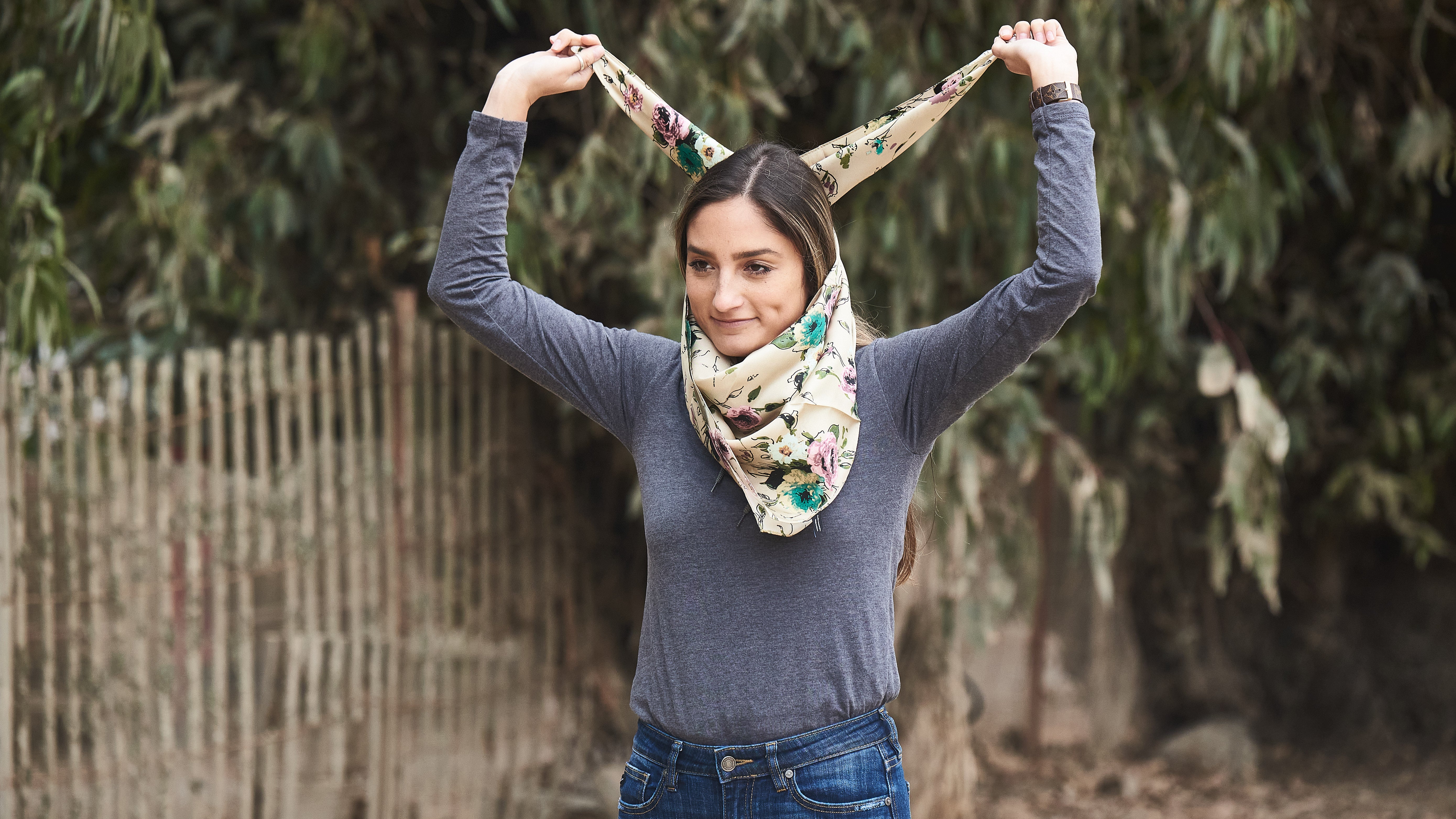 Pick up the wild rag and keep the triangle pointed downward on your chest. Bring the two ends up, over, and around your neck.