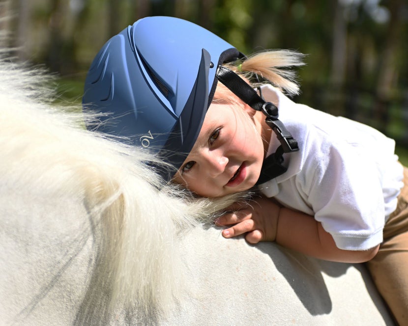 Young rider on her pony wearing a blue Ovation Deluxe Schooler Dial-Fit Riding Helmet.
