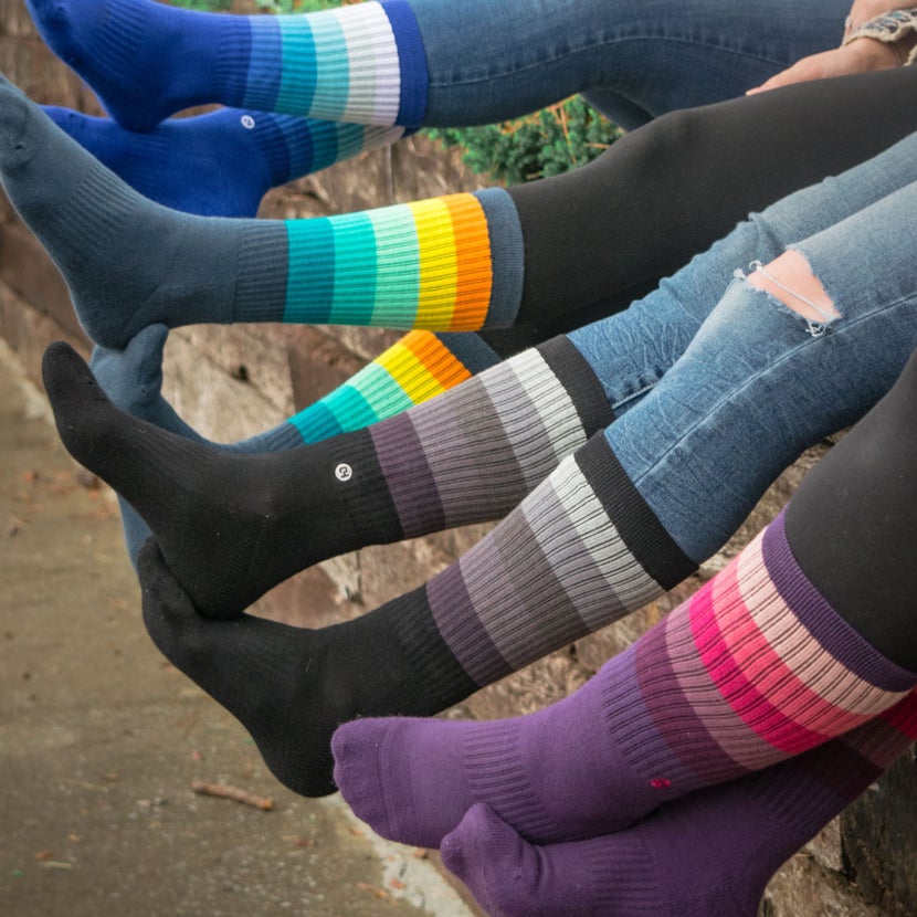 Row of girls sitting on a wall showing off their colorful C4 riding socks.