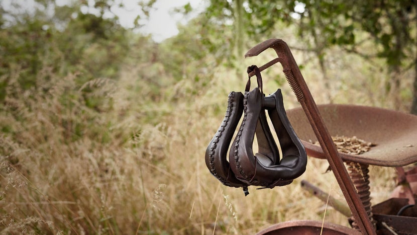 The Tucker Leather Laced ErgoBalance Western Stirrups hanging off of an old, red tractor. 