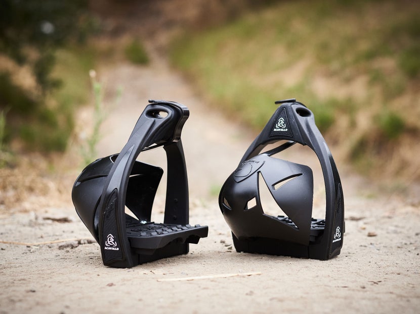 The Burioni Flexia Endurance Stirrups sitting on a dirt pathway, with grass in the background. 
