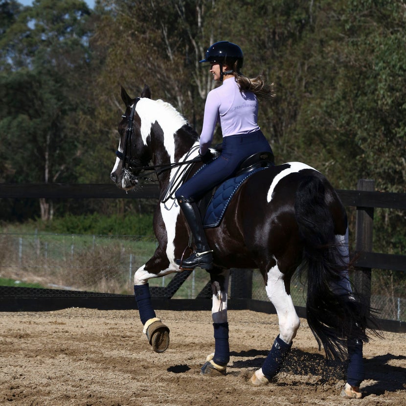 Women riding a paint horse wearing Performa Ride Luna top and Evolve tights. 