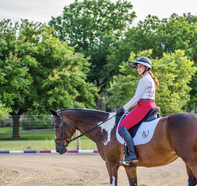 Equestrian sitting on horse in arena setting, using a Soless Classic helmet visor