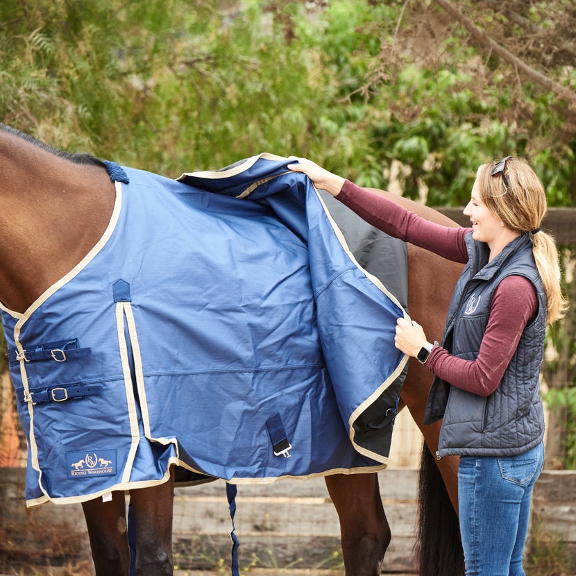 Girl placing blanket on her horse after buckling front clips.