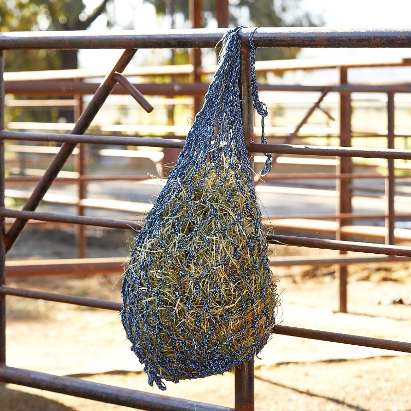 Niblet Hay Net Slow Feeder hanging on a fence. 