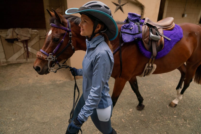 Rider leading a bay horse, saddled with a purple Toklat CoolBack pad. 